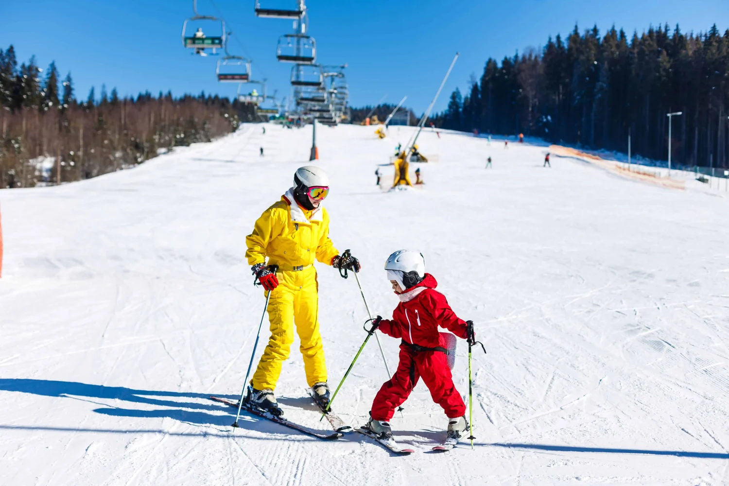 Family enjoying a sunny ski day with young children learning to ski